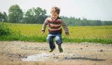 Child jumping in puddle