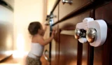 toddler standing next to a child safety lock