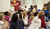 Children in a classroom with hands up