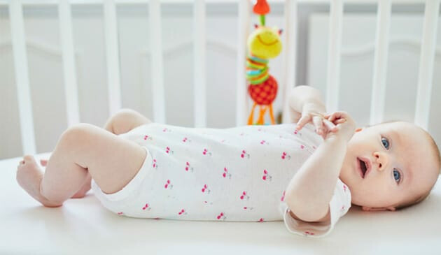 Baby playing in co-sleeper cot