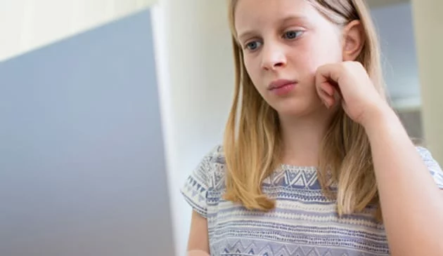 sad girl looks at computer monitor