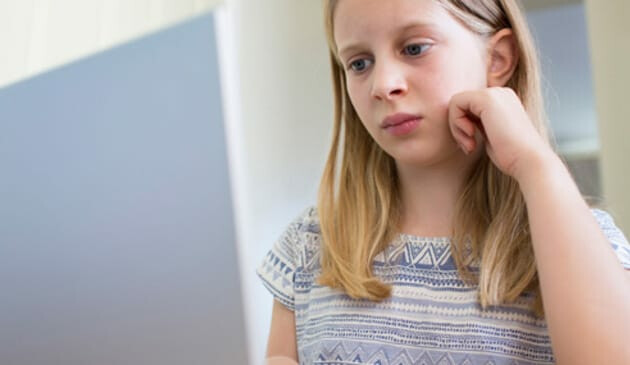 sad girl looks at computer monitor