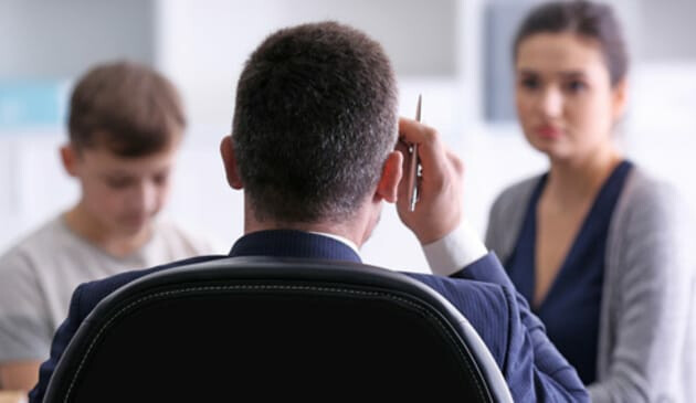 mother and child talk to man in office