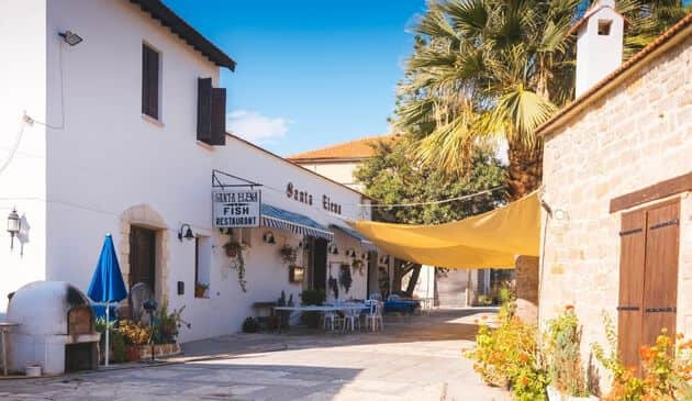 Short, stone buildings with a yellow canopy connecting the buildings together with a seating area underneath