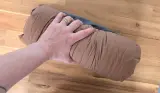 A hand squeezes the Decathlon Quechua Camping Pillow Ultim Comfort