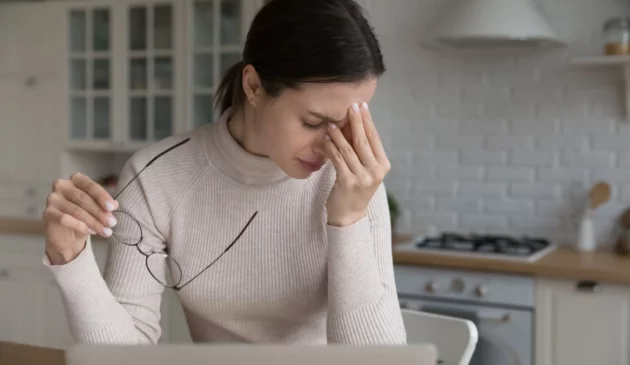 A woman is experiencing burnout and holds her head