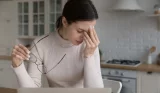 A woman is experiencing burnout and holds her head