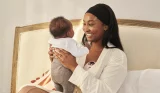 A mother holds her baby in bed