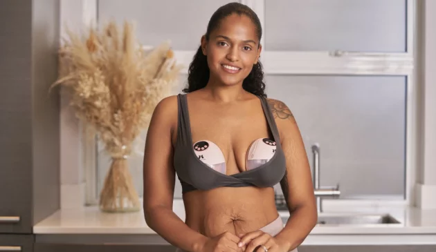 A woman stands with Fraupow's breast pumps in her bra