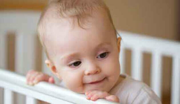 Eight month old standing up in cot
