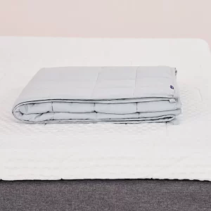 A product image of the Emma Hug Weighted Blanket atop a bed