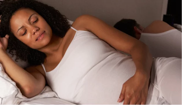 Woman holding pregnant bump in bed