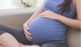 Pregnant woman on sofa holding bump