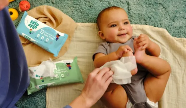 Child laying on blanket next to Fred & Flo baby wipes