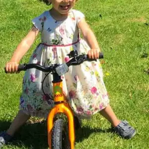A girl in a dress riding a Frog Tadpole balance bike