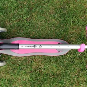 A folded Globber Primo scooter laying on the grass