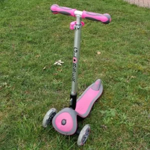 Pink Globber Primo scooter on the grass