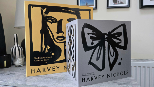 The yellow Harvey Nichols Beauty Advent Calendar 2026 sleeve standing behind a grey 12 Days of Fragrance Advent Calendar 2026 box, which has a black brushstroke bow on the front