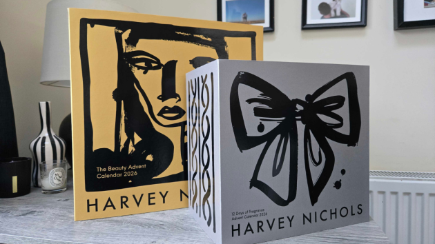 The yellow Harvey Nichols Beauty Advent Calendar 2026 sleeve standing behind the grey 12 Days of Fragrance Advent Calendar 2026 box, which has a black brushstroke bow on the front