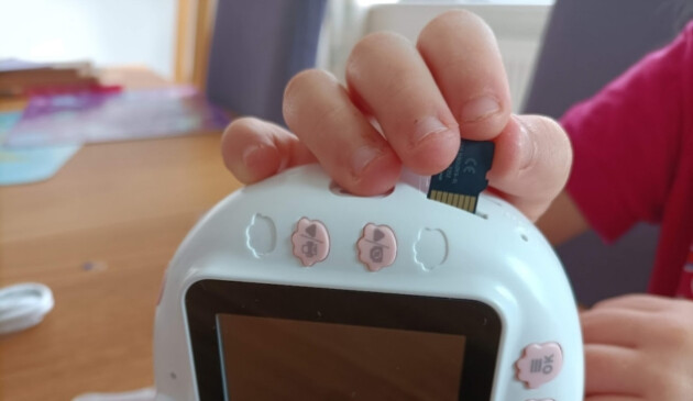 Close up of a child's hand putting the memory card in the HelloBaby camera