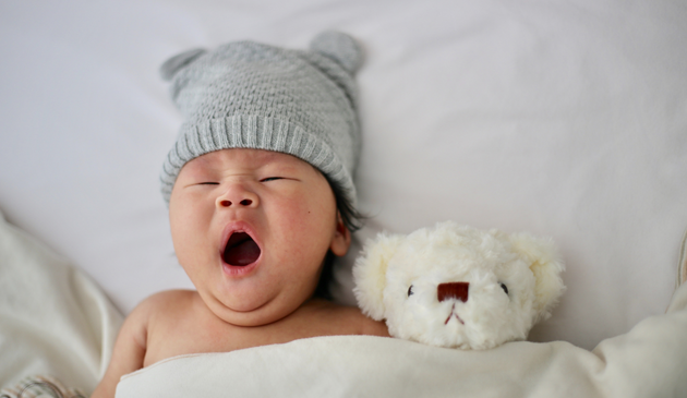 baby in a cute hat with a teddy, yawning