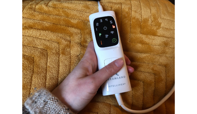 a hand holding a controller on a yellow blanket