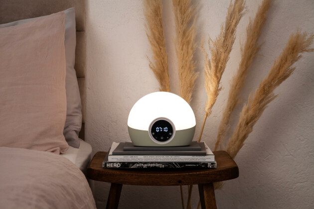 The Lumie Bodyclock Spark 100 on a bedside table while lit