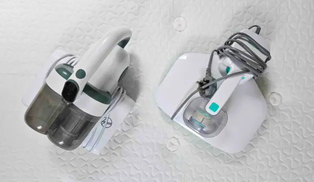 The Hoover HMC5 is on a bed next to Spring & Spruce's Mattress Maid
