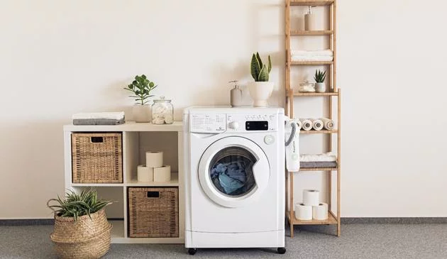 A picture of a washing machine between shelving with clothes washing inside.