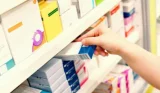 Hand taking medication off pharmacy shelf