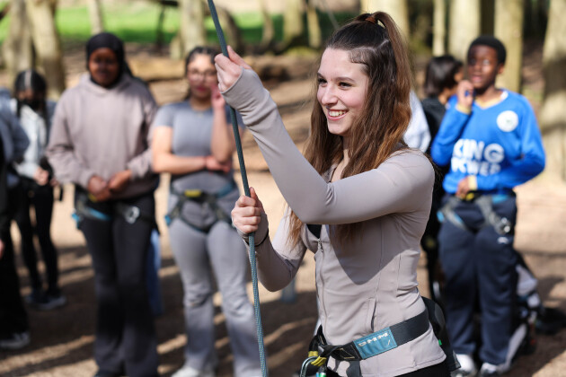 A teenage girl is smiling, about to abseil as part of a school day trip