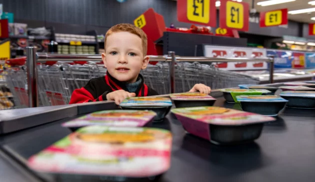 A little boy is at the tills in Iceland with the Little Explorers range on the belt