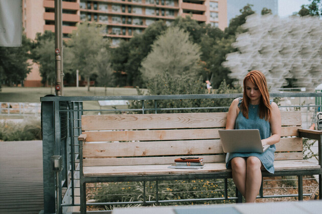 A woman on a laptop on a park bench
