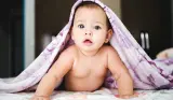 a baby under a purple blanket