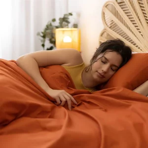 A woman sleeps underneath the A product image of the Karmara Karma Switch Weighted Blanket