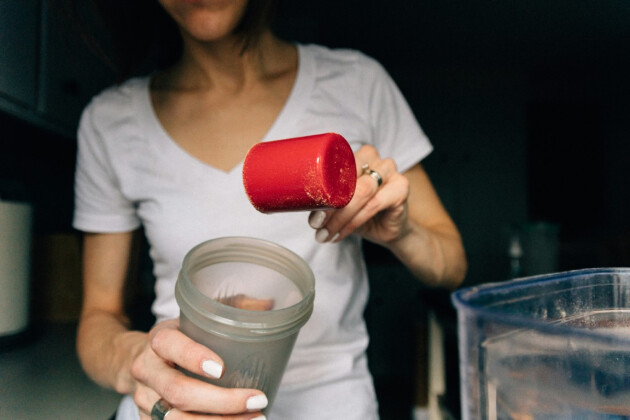 A woman puts protein powder in a drink