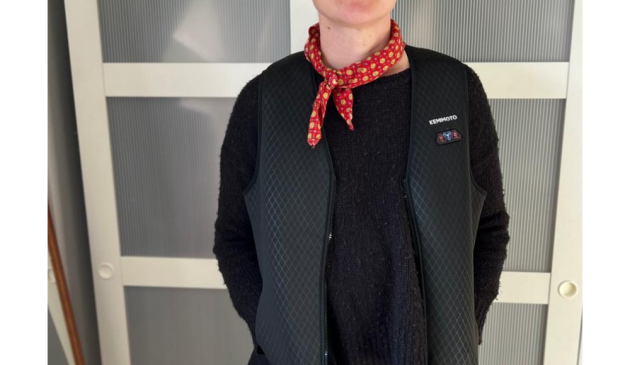 A woman wearing the Kemimoto Heated Vest with a black knitted jumper and red neckerchief