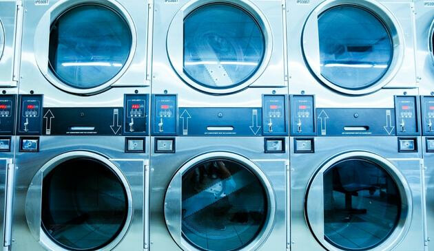 A picture of washing machine and tumble dryers in a laundrette.