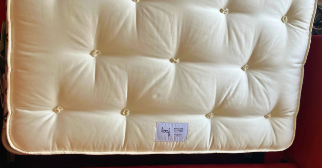 Close-up of the tufted cream Loaf sofa bed mattress and brand label