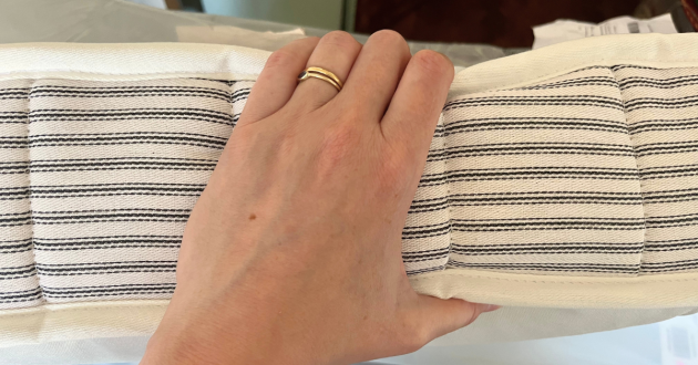 Hand holding the striped edge of the Loaf sofa bed mattress to show its depth and stitching