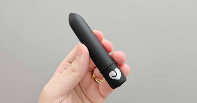 A hand holds the Lovehoney Magic Bullet 10 Function bullet vibrator against a wall