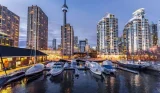 CN Tower and lit up skyscrappers overlooking harbour with yachts in an evening