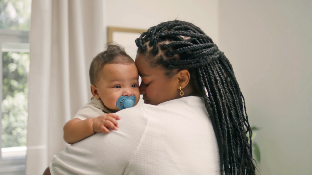 A mother holding her young baby with a MAM dummy over her shoulder
