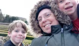 A mum and her two boys smile at the camera
