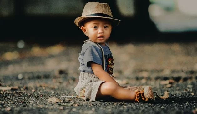 baby. sitting in dungarees and hat