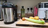 Morphy Richards Saute & Soup Maker positioned on a kitchen worktop next to olive oil, potatoes and leek ingredients