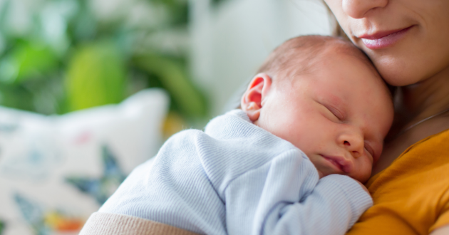 Mother cuddling sleeping newborn
