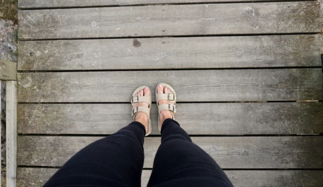 Photo looking down at a pair of legs wearing skinny jeans and Birkenstock sandals
