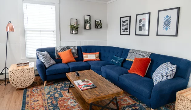 A living room with a blue corner sofa and colourful cushions