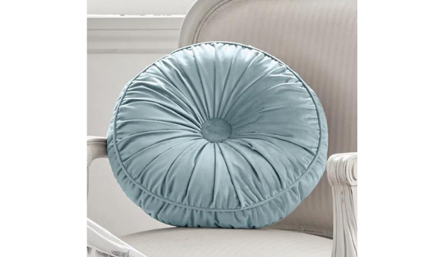 A pale blue round cushion on an off-shite chair